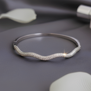 Inspired by the calm rhythm of the sea, the Onda Bangle Bracelet features a graceful wavy curve that wraps your wrist in effortless elegance. Crafted in sleek 925 silver, this piece is perfect for adding a touch of fluid sophistication to your everyday look or styling with other jewelry pieces for a modern, stacked style.