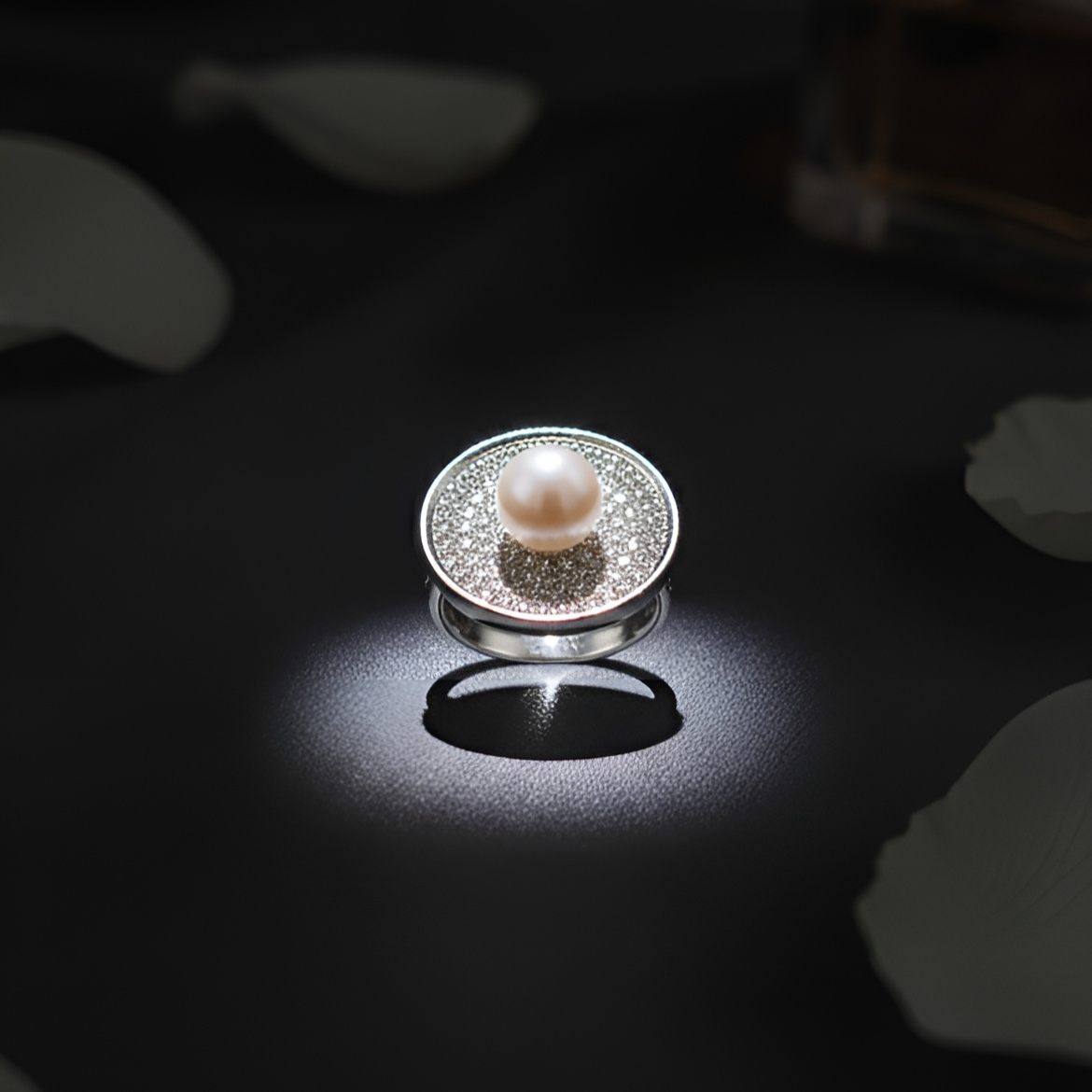 Inspired by the quiet brilliance of the ocean’s rarest jewel, Morvarid celebrates the eternal allure of pearls. Crafted in fine silver, this signature ring features a luminous central pearl set on a sculptural circular base — bold yet serene, radiant yet composed.